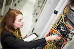 Technician holding digital tablet while examining server in server room