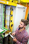 Technician using digital tablet while analyzing server in server room