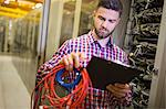 Technician holding patch cable and reading notes in server room