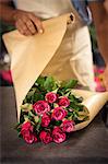 Close-up of male florist wrapping flowers in paper at his flower shop