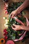 Close-up of male florist tying poly ribbon on bouquet of flower at his flower shop