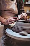 Midsection of craftsman making ceramic container in workshop