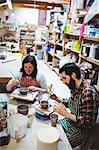 Female potter with colleague making pots at workshop