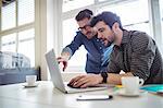 Photo editor showing coworker on laptop at creative office