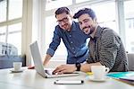 Portrait of smiling photo editors using laptop in creative office