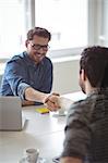 Happy business people greeting each other with handshake in creative office