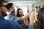 Creative business people fixing sticking notes on glass in office