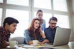 Business people looking at laptop in meeting room at creative office