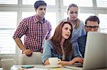 Businesswoman with coworkers using laptop in meeting room at creative office