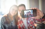 Happy couple taking selfie from cellphone at cafe