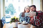 Happy young couple video chatting at cafe