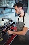 Handsome young waiter using espresso maker at cafe