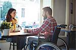 Disabled hipster with young woman at cafe