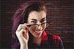 Young woman smiling at camera against brick wall