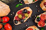 Italian bruschetta with cherry tomatoes, herbs, olives, mozzarella on toasted crusty ciabatta bread