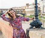 Remarkable holiday in Florence. Portrait of happy woman in a dress on the embankment near Ponte Vecchio