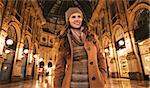 Get ready to making your way through shopping addicted crowd. Happy young woman standing in Galleria Vittorio Emanuele II and looking aside
