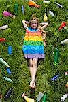 Young girl happy in the grass surrounded by plastic waste - unaware of the danger