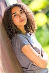 Beautiful mixed race African American girl teenager female young woman outside, arms folded in spring or summer looking sad depressed or thoughtful
