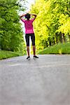 Beautiful mixed race African American young woman girl teenager fitness running jogging resting on road lined with spring or summer green trees