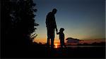 father and son silhouette on sunset