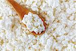 crumbly cottage cheese in the wooden spoon lying diagonally upwards