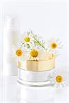 chamomile and jars of cream on the white background