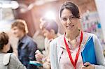 Portrait smiling woman holding folder at technology conference