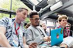 Men using laptop in audience at conference