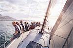 Retired friends sitting on sailboat on sunny ocean