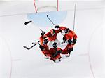 Overhead view hockey team in red uniforms huddling on ice