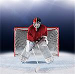 Portrait determined hockey goalie protecting goal net on ice