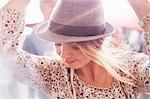 Close up young blonde woman with fedora dancing at music festival