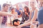 Young friends hanging out drinking beer and talking at music festival