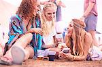 Young friends hanging out drinking and texting at music festival