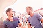 Young men drinking and laughing at music festival