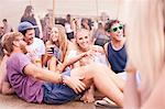 Young friends hanging out drinking and talking at music festival