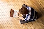 Man sitting indian style on floor using laptop computer