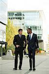 Businessmen having conversation while walking on sidewalk