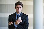 Businessman text messaging with cell phone, portrait