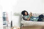 Woman text messaging while relaxing at home