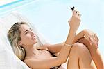 Woman relaxing by pool with smartphone