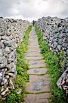 England, North Yorkshire, Grassington. A lone person walking on a footpath between dry stone walls typical of the Yorkshire Dales. MR.