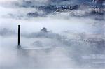 England, Halifax. Mill chimney and houses appearing through mist.