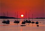 England, Isles of Scilly, St Marys. Sunset through boats at Porth Mellon.