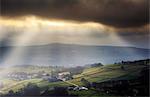 England, West Yorkshire, Calderdale. Sunlight shining through clouds onto mills and houses near Halifax.