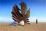 England, Suffolk, Aldeburgh. Tourist taking a photograph of the scallop shell sculpture by Maggi Hambling. MR.