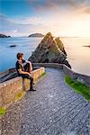 Dunquin pier (Dún Chaoin), Dingle peninsula, County Kerry, Munster province, Ireland, Europe. A man watching the sunset on the trail.