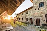 Grazzano Visconti, Vigolzone, Piacenza district, Emilia Romagna, Italy. Woman walking in a old couryard of the town.