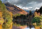 Scotland, Glencoe. Snow capped mountains reflected in a small loch in the autumn.